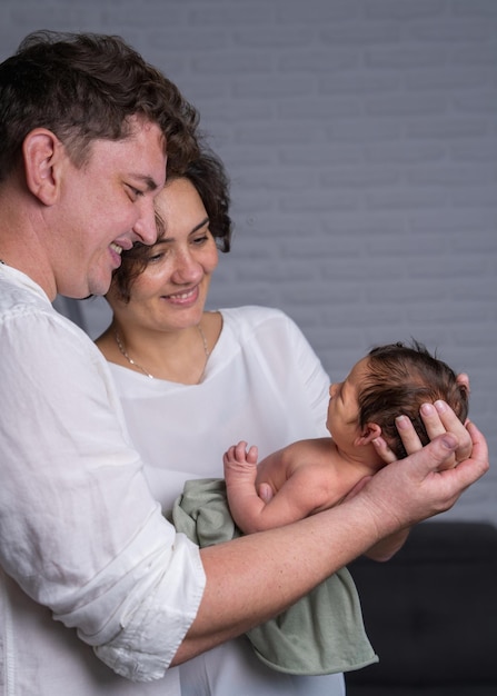 Happy family with a newborn baby Mom and dad looking tenderly at the baby