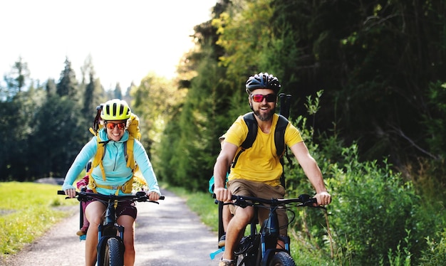 Happy family with small children cycling outdoors in summer nature.