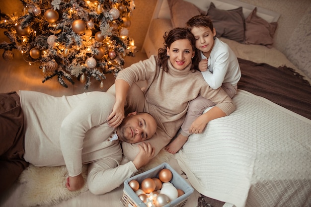 happy family with son under christmas tree in the bedroom