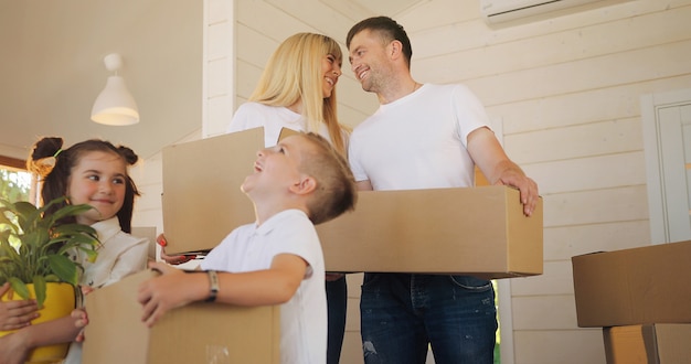 Happy family with two children at new home holding boxes