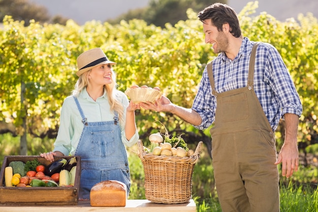 Happy farmer couple handing eggs