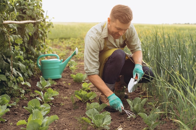 Happy farmer man waters the beds and works in the garden