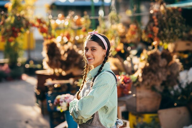 Happy farmer woman in denim overalls smiling sincerely while posing