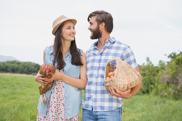 Happy farmers holding chicken and eggs