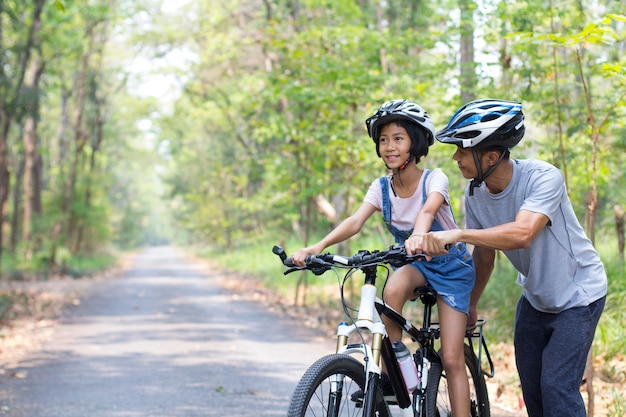 Happy father and daughter cycling in the park