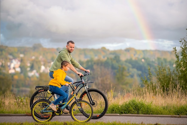 Happy father and daughter take bike ride in nature in autumn.