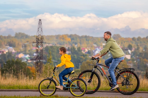 Happy father and daughter take bike ride in nature in autumn