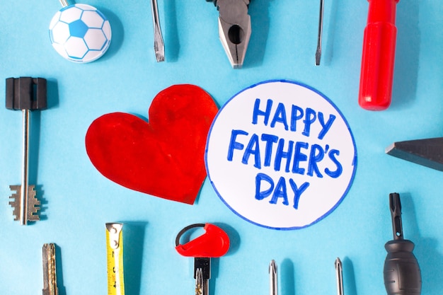 Happy father day flat lay. Blue surface with tools and a heart with the inscription Happy Fathers Day . Copy space for text.