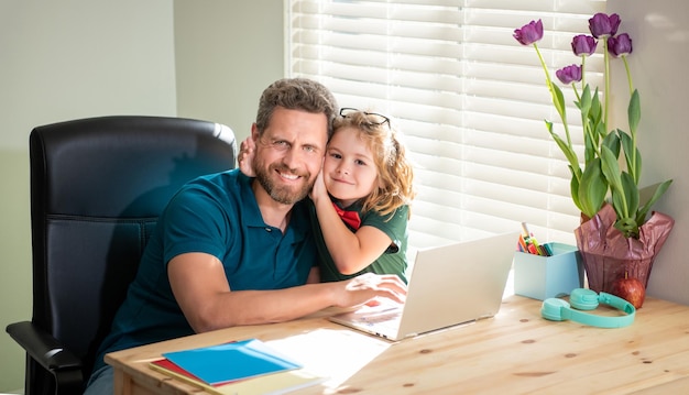 Happy father helping his school son study with laptop at home childhood