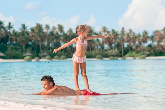 Happy father and his adorable little daughter at tropical beach walking together