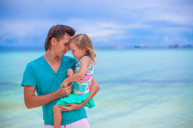 Happy father and his adorable little daughter at white sandy beach