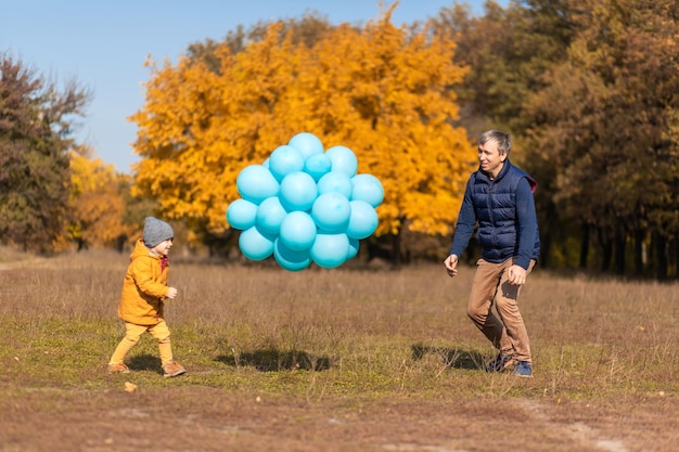 Happy father is enjoying spending the day off with his child in the autumn park Play with balloons