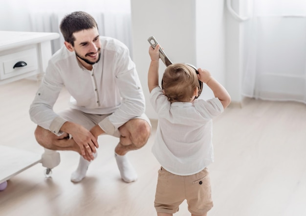 Photo happy father and little son are playing in the kitchen the kid is playing with a bowl family lifestyle