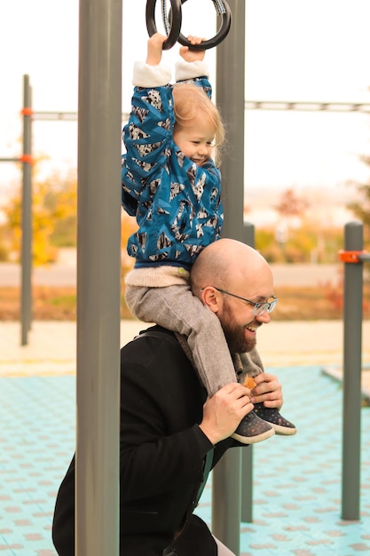 Happy father playing with little daughter on the playground in city park. Family fun. Family time