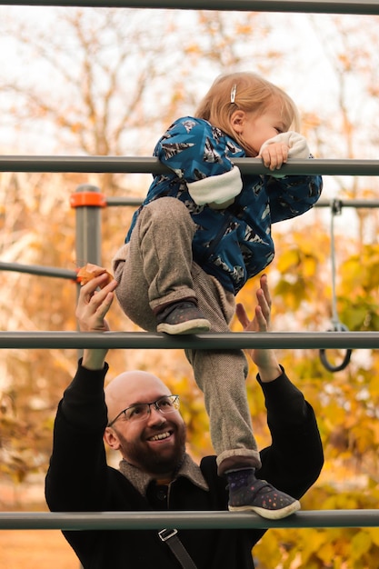 Happy father playing with little daughter on the playground in city park. Family fun. Family time