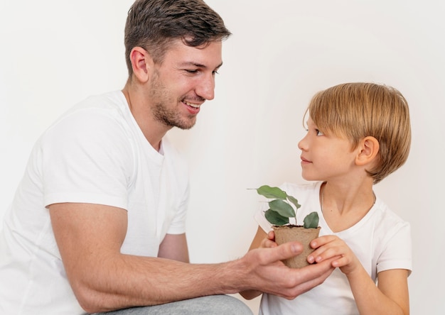 Happy father and son holding pot of plant