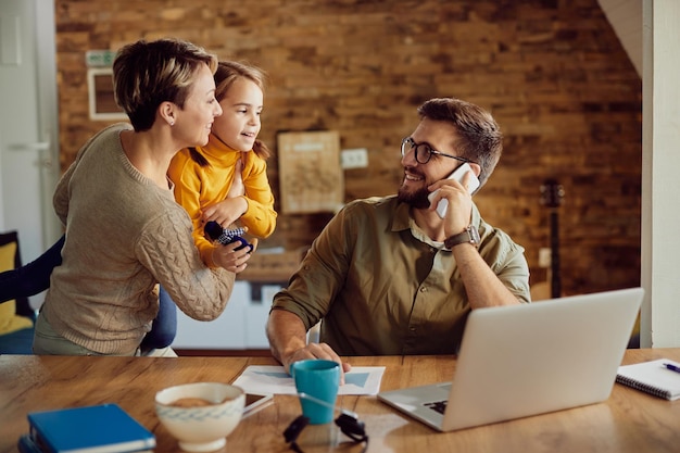 Happy father talking to his family while working at home