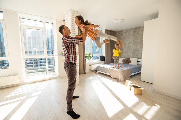 happy father and two children playing and cuddling at home on floor