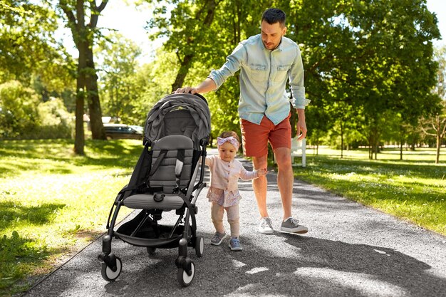 Photo happy father with child in stroller at summer park