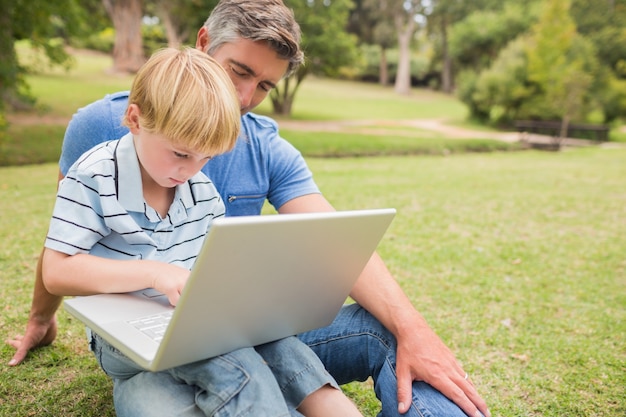 Happy father with his son using laptop in the park