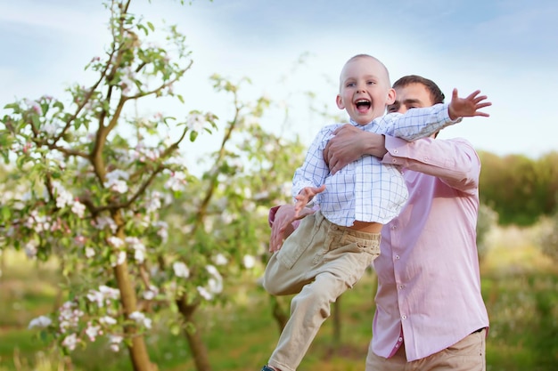 Happy father with a little son in a blooming garden Dad's Day Throw the child up