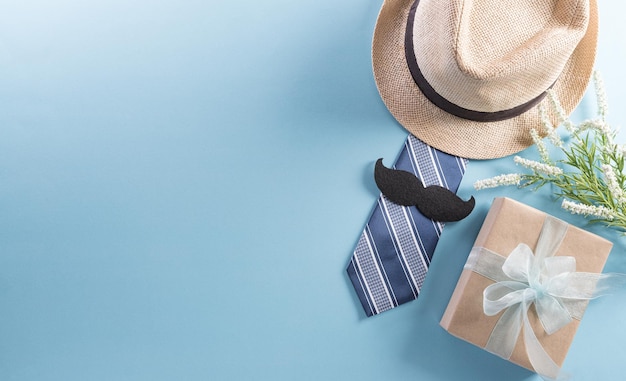 Happy Fathers Day background concept with hat gift box necktie and mustache on pastel background