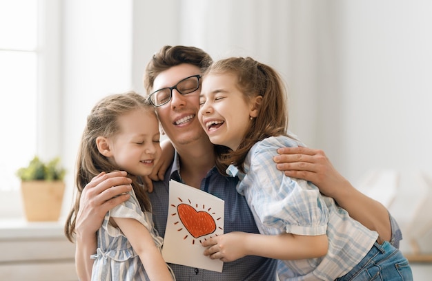 Happy fathers day Children daughters congratulating dad and giving him postcard