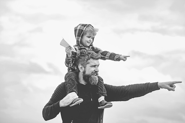 Happy fathers day Dad and son are playing on sky background Father and son building together a paper