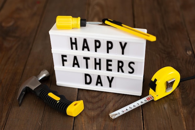 Happy Fathers Day Father's lightbox message with tools on wood background Greeting card concept