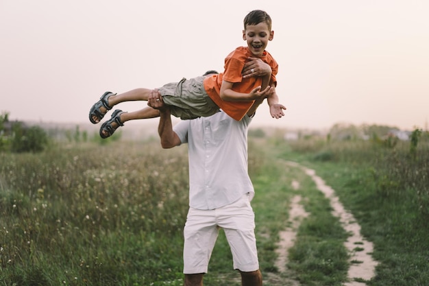 Happy Fathers day Father with son are walking in the field Dad hugs boy The concept of Fathers day relationships with children care and love