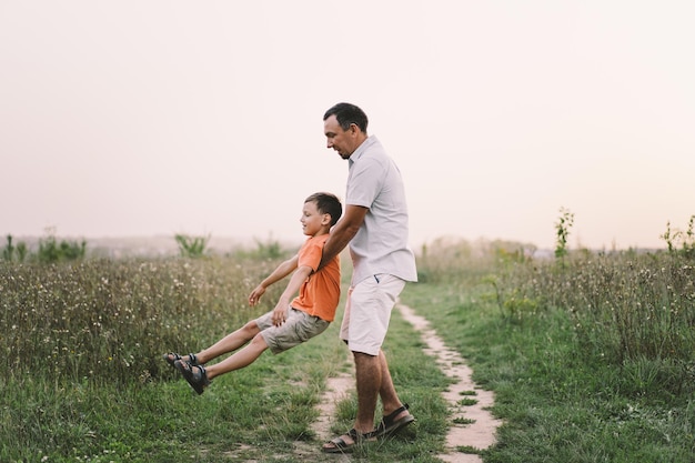 Happy Fathers day Father with son are walking in the field Dad hugs boy The concept of Fathers day relationships with children care and love