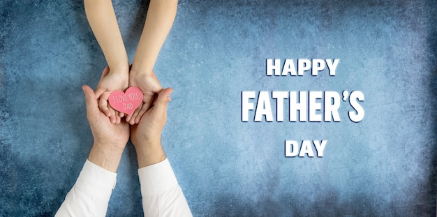 Photo happy fathers day greeting cardgift in the hands of daughter and father on a blue background