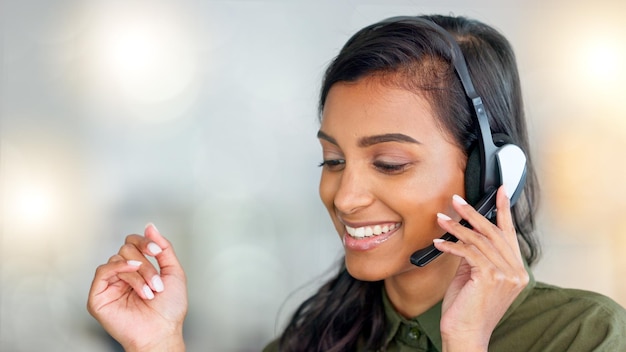 Happy female customer service agent smiling while working in a call centre and talking to a client with a headset A helpful saleswoman assisting customers with purchase orders and questions online