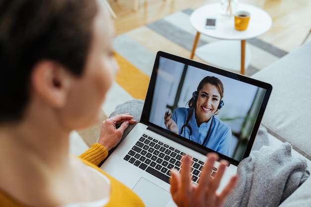 Happy female doctor having video call over a computer with a patient who is sitting at home