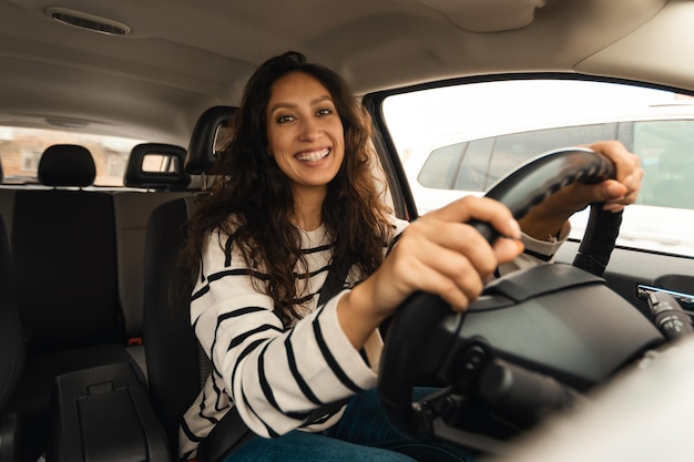 Happy female driving car smiling to camera posing in auto