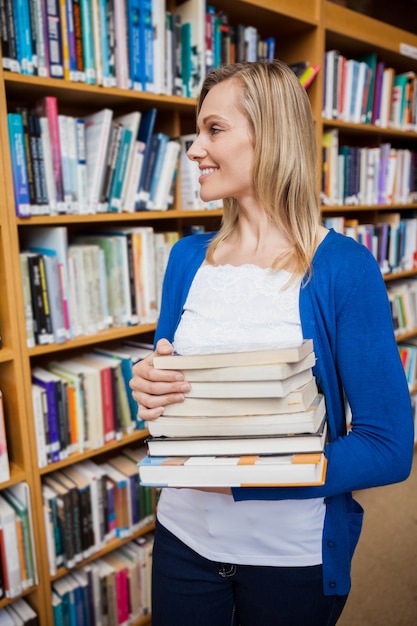 Happy female student taking books in the library at the university