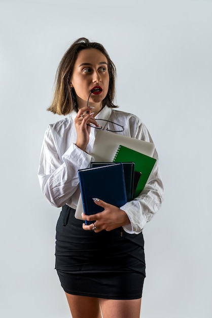 Happy female teacher or businesswoman holding books and smiling on background