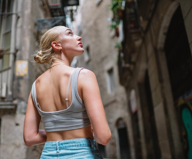 Happy female tourist backwards walking in old town alley Barcelona Spain