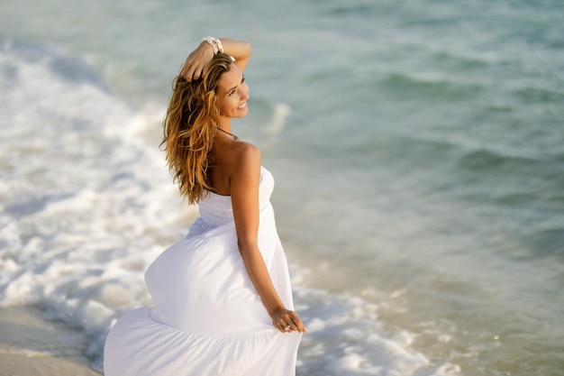 Happy feminine woman in sundress enjoying in summer by the sea