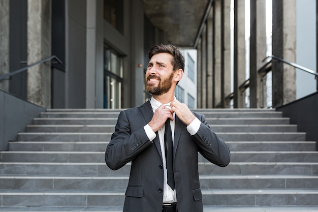 Happy fired office worker, rejoices and laughs. Satisfied the employee throws out a tie. Portrait of a free man. outside, near office building concept: job loss, freedom, new life, startup, start end