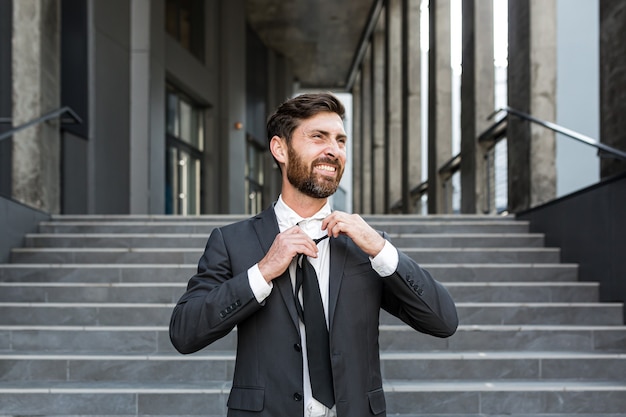 Happy fired office worker, rejoices and laughs. Satisfied the employee throws out a tie. Portrait of a free man. outside, near office building concept: job loss, freedom, new life, startup, start end