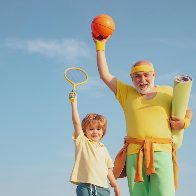 Happy fit senior man exercising portrait of a healthy father and son working out over blue sky backg