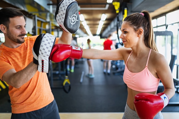 Happy fit woman exercise boxing with personal trainer at the gym. Sport, health, people concept