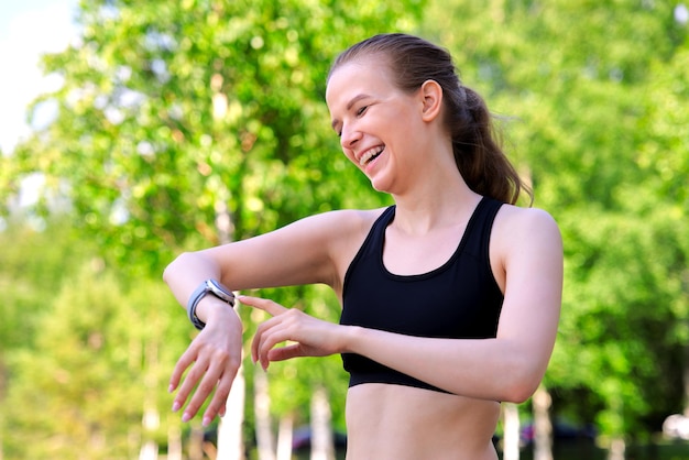 Happy fit woman is jogging running checking smart watches looking at smartwatches tracking pulse