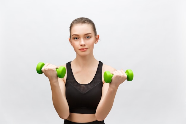 Happy fitness woman lifting dumbbells smiling cheerful, fresh and energetic. Caucasian fitness girl training  