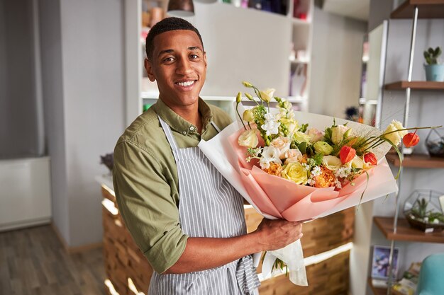 happy floral artist holding a bunch of colourful flowers in a wrapping