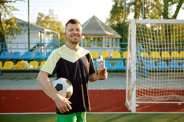 Happy football player drinking water from bottle during break time Recreational pursuit on weekend