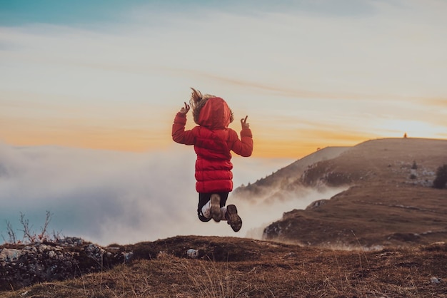 A happy freedom girl joyfully jumps on the top mountain