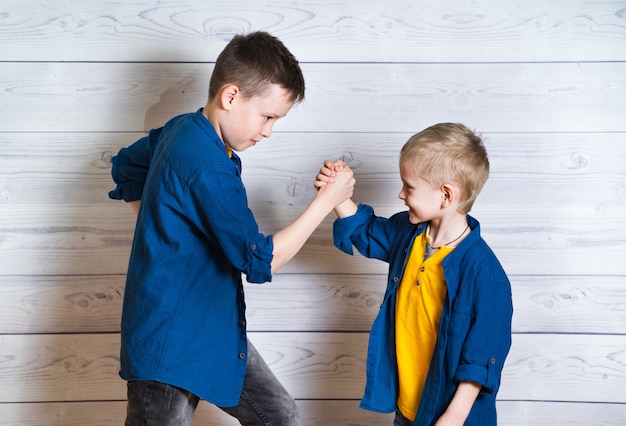 Happy and friendly brothers during the game of arm wrestling. Two positive friends fighting by hands