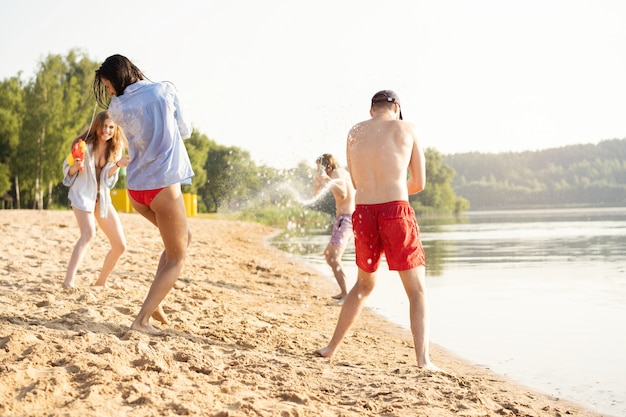 Happy friends doing battle with water guns - Youth, summer lifestyle and holiday concept